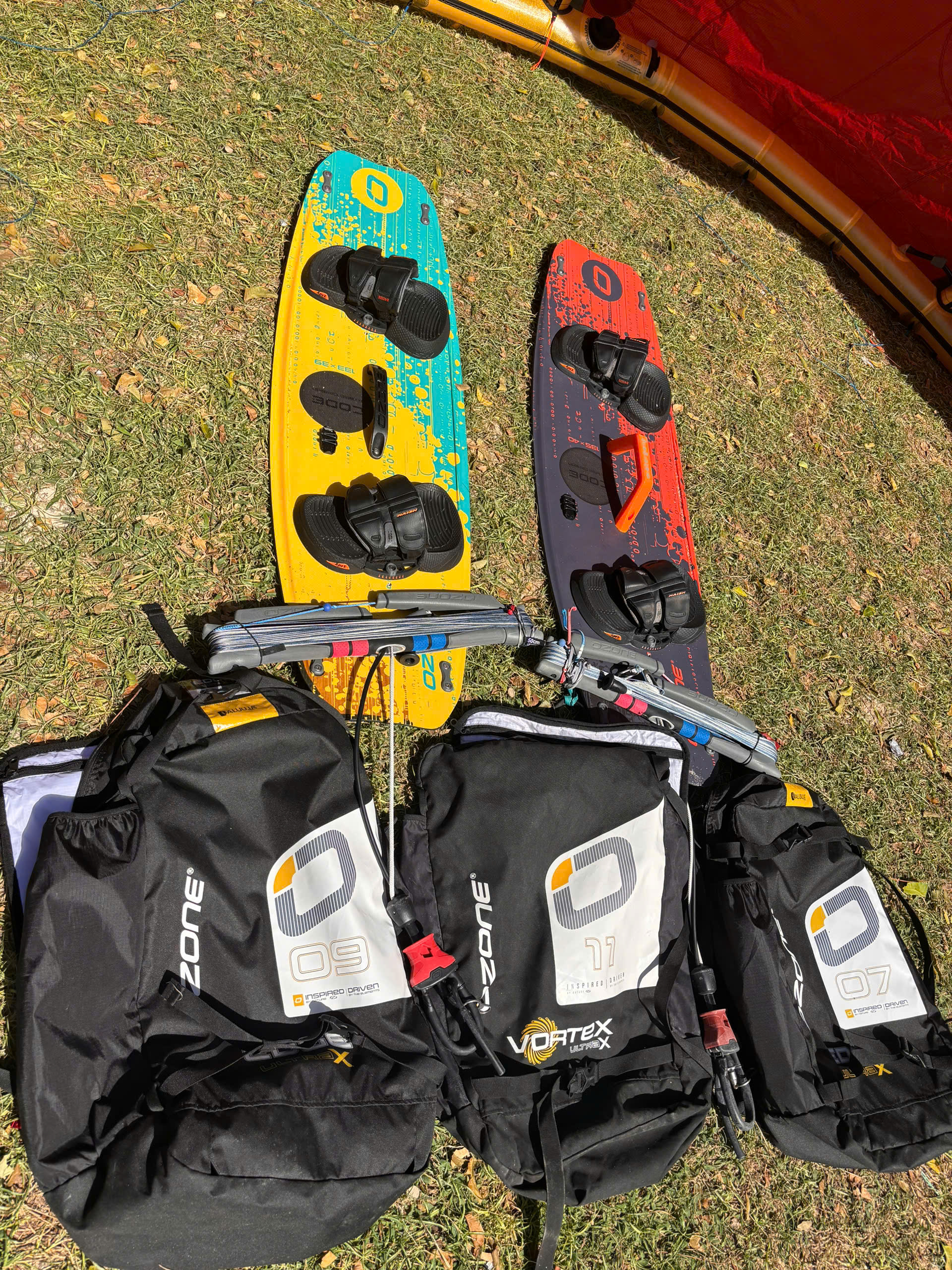 Kiteboards and equipment laid out on the grass